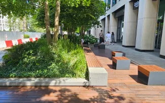 Sitzbereich mit Bänken, Holzbelag und Grünflächen